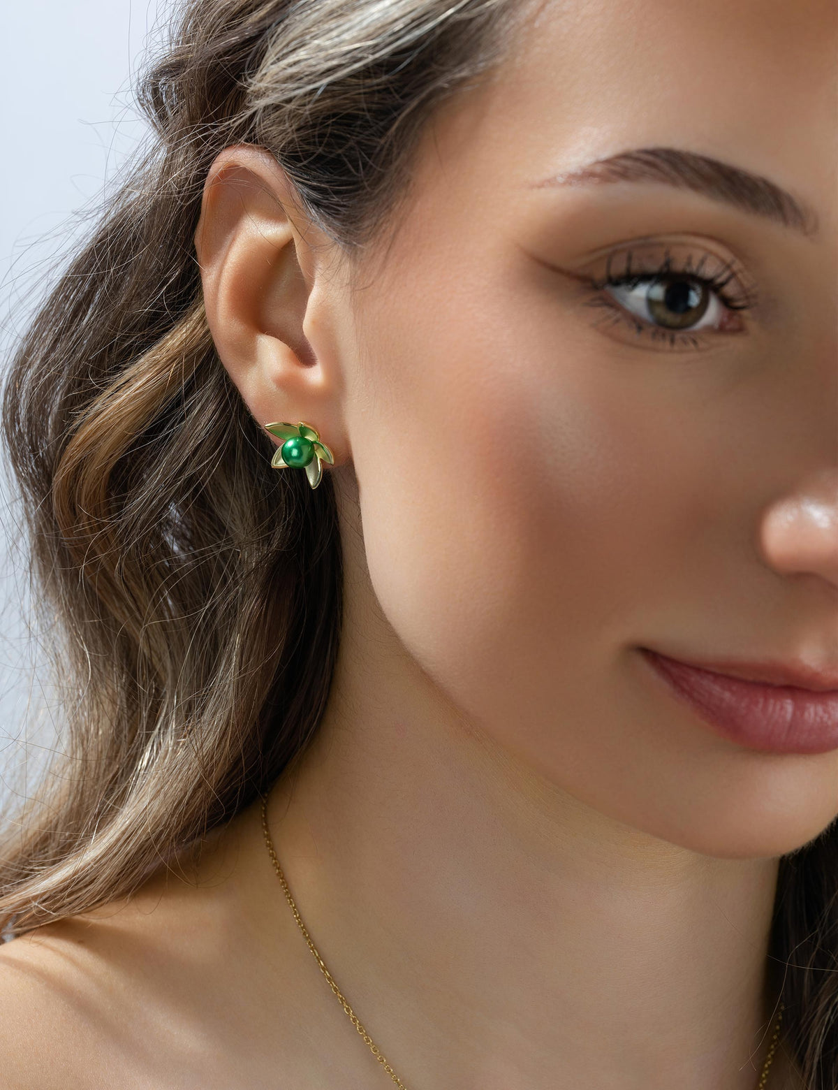 Ohrstecker Seerose 925/- Silber goldplattiert mit Muschelkernperle smaragd am Ohr getragen, Nahaufnahme