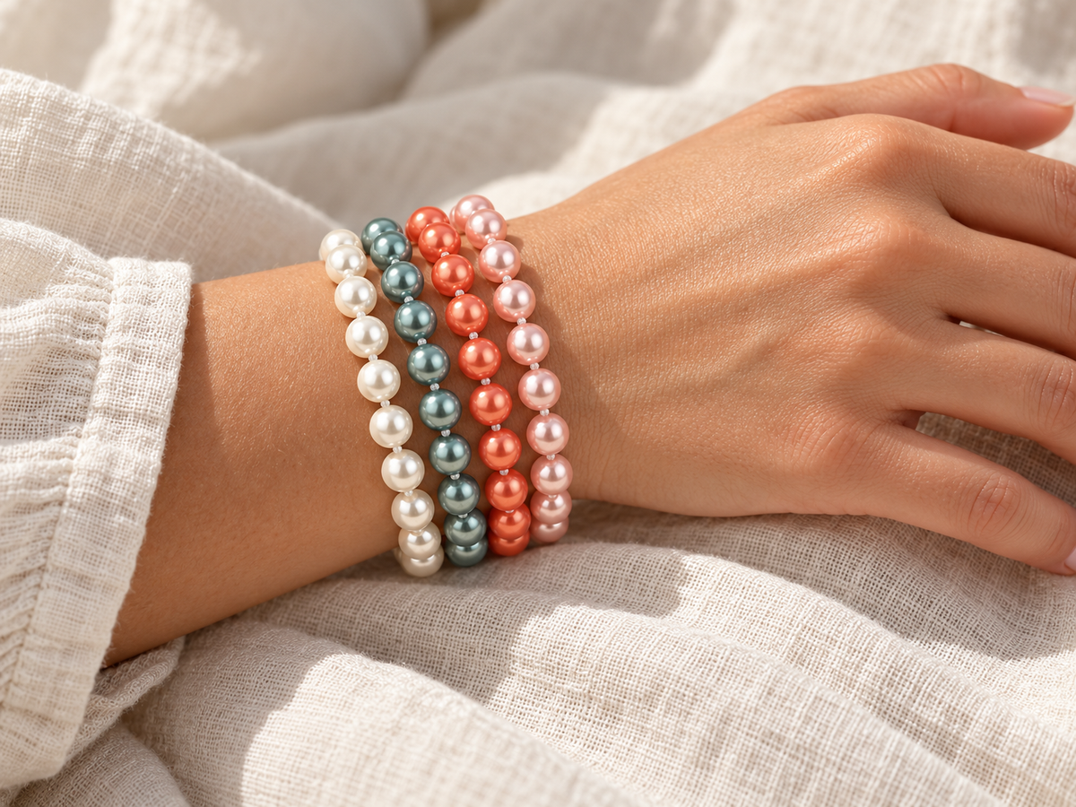 Vier Essentials Flexarmbänder mit Muschelkernperlen in Weiß, Petrol, Papaya und Rosé am Handgelenk