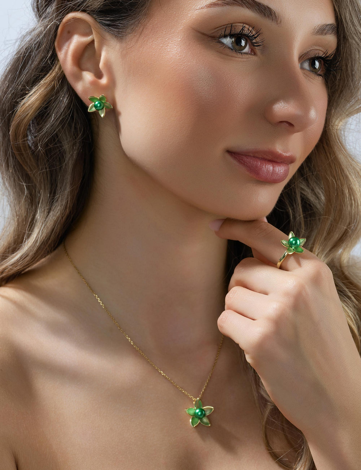 Ohrstecker Seerose 925/- Silber goldplattiert mit Muschelkernperle smaragd getragen, Porträt mit Hand am Kinn